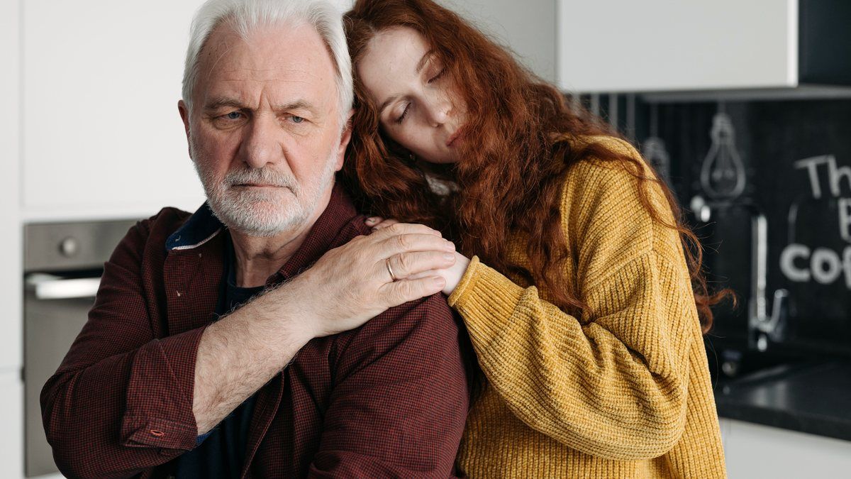 A father holding his grown daughter as she grieves
