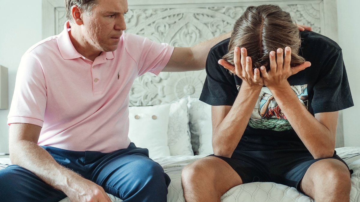 A man sitting close beside a grieving teenager