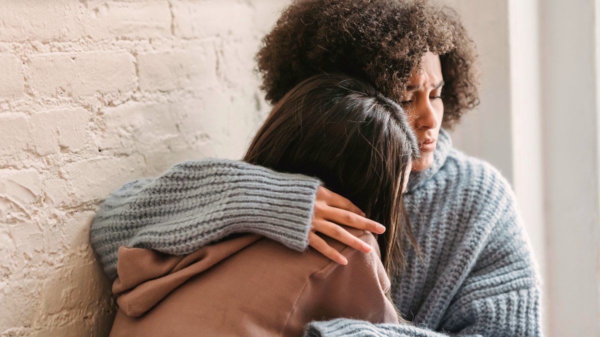 Two women holding each other at home